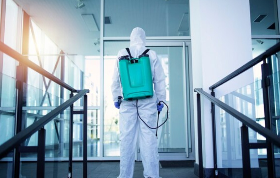 Medical staff wearing white protective clothing disinfecting